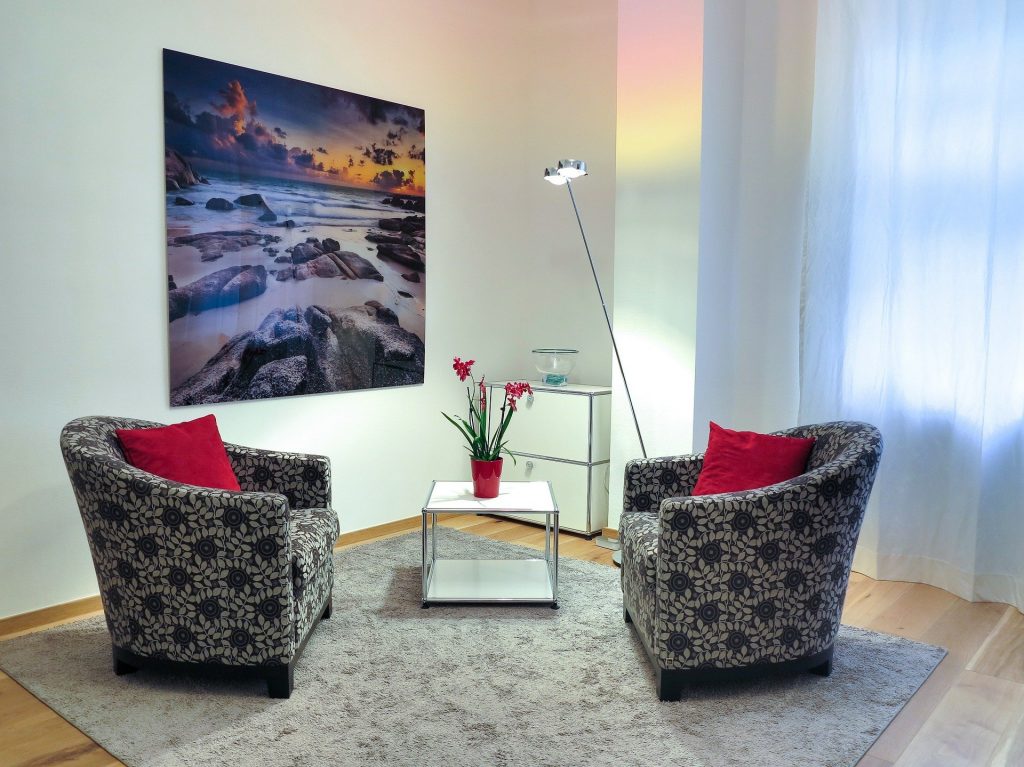 CBT therapist room with two armchairs facing each other a large painting of a rocky beach on wall